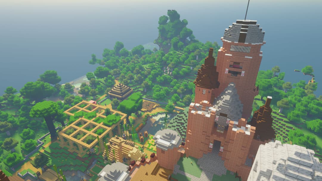 An aerial view of a tall brick castle overlooking jungle trees, farms, and smaller buildings.